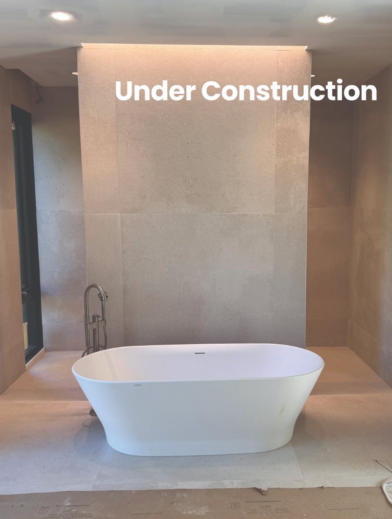 Bathroom renovation under construction with concrete walls and a large bath tub in the center of the room